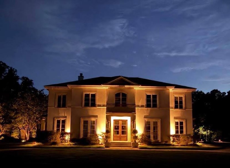 Large stucco estate facade illuminated in warm architectural light at dusk